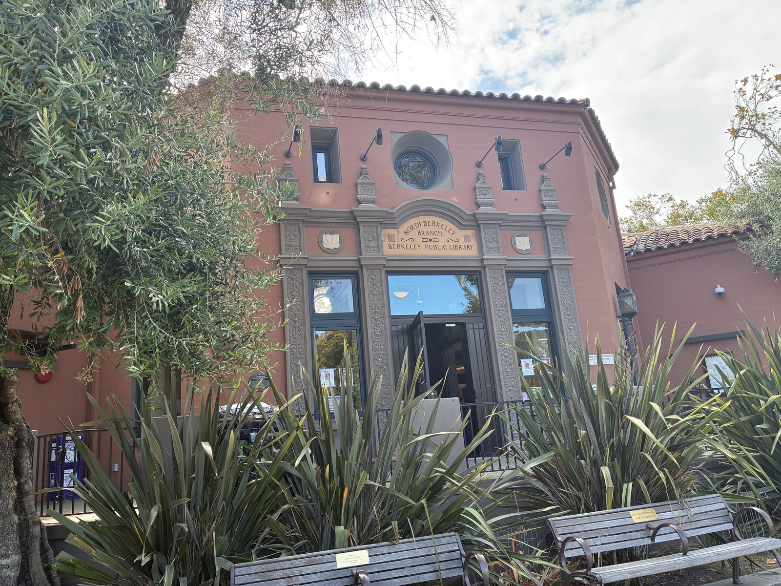 The North Berkeley branch library, a pink Spanish-style building with benches out front