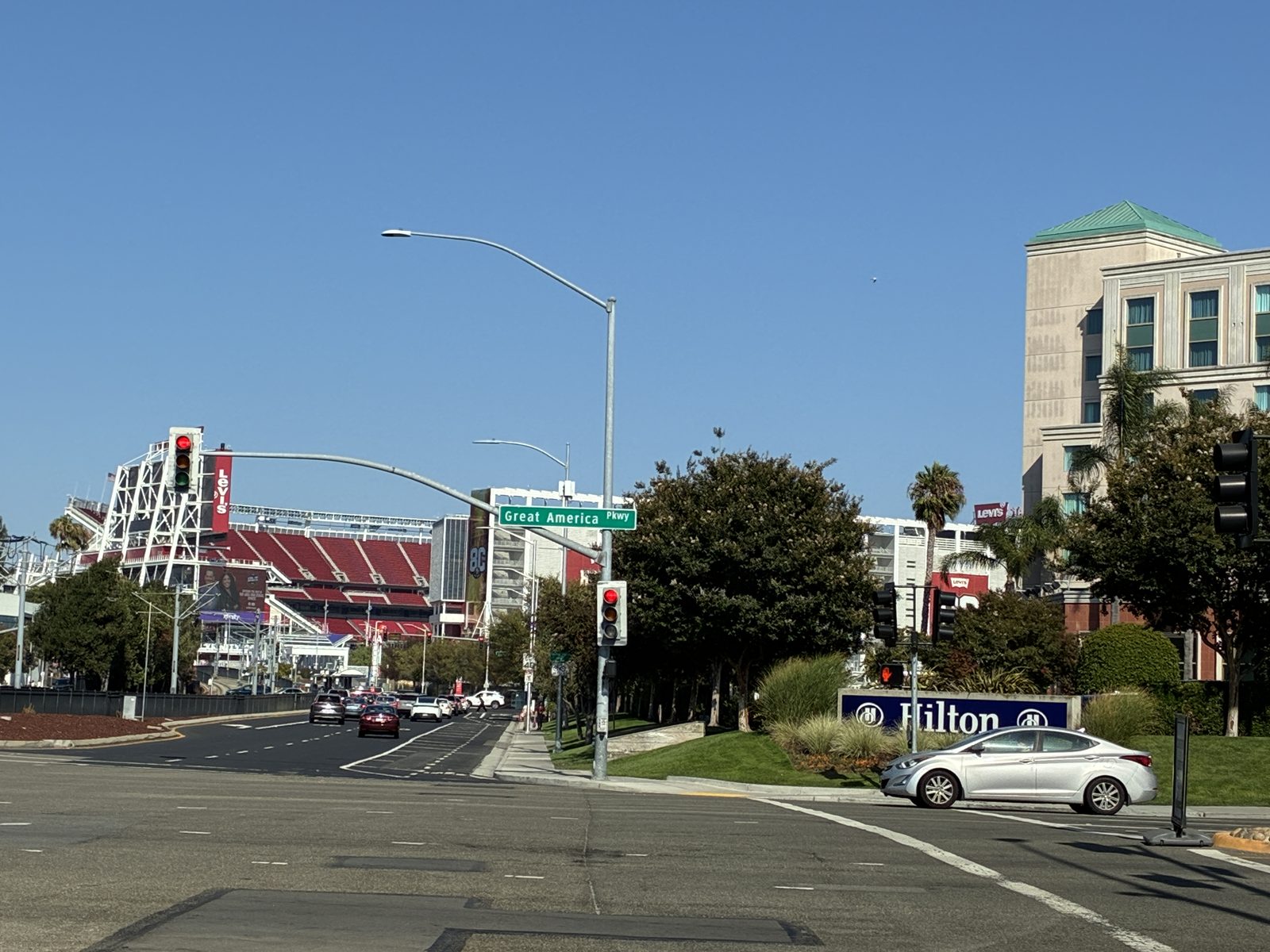 An intersection outside the stadium, traffic signals and a hotel sign in the afternoon sun
