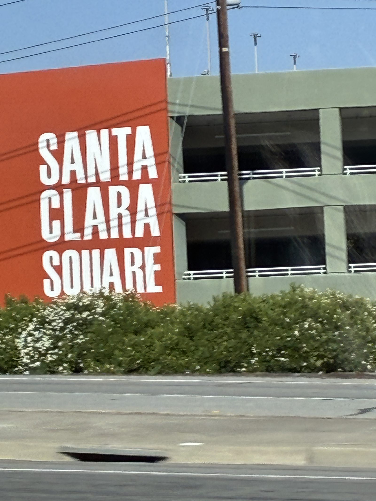 An orange wall lettered SANTA CLARA SQUARE beside a parking structure