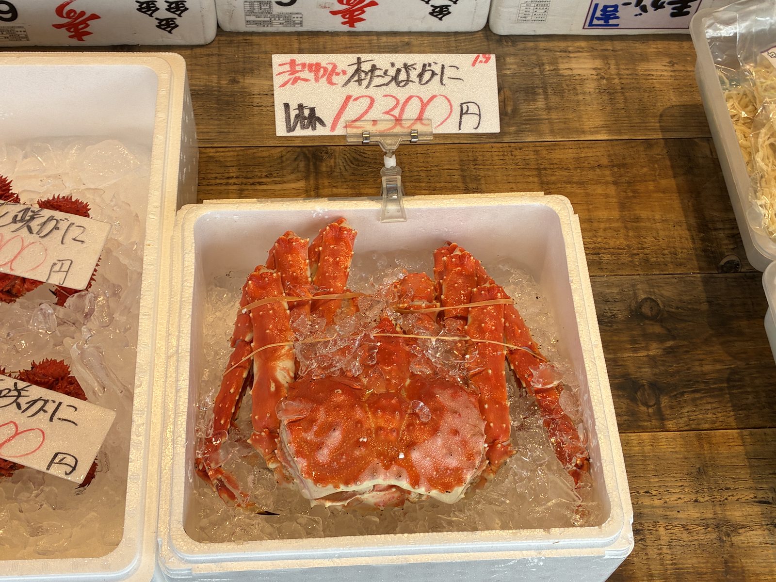 A whole king crab on ice in a tray, the price written above it