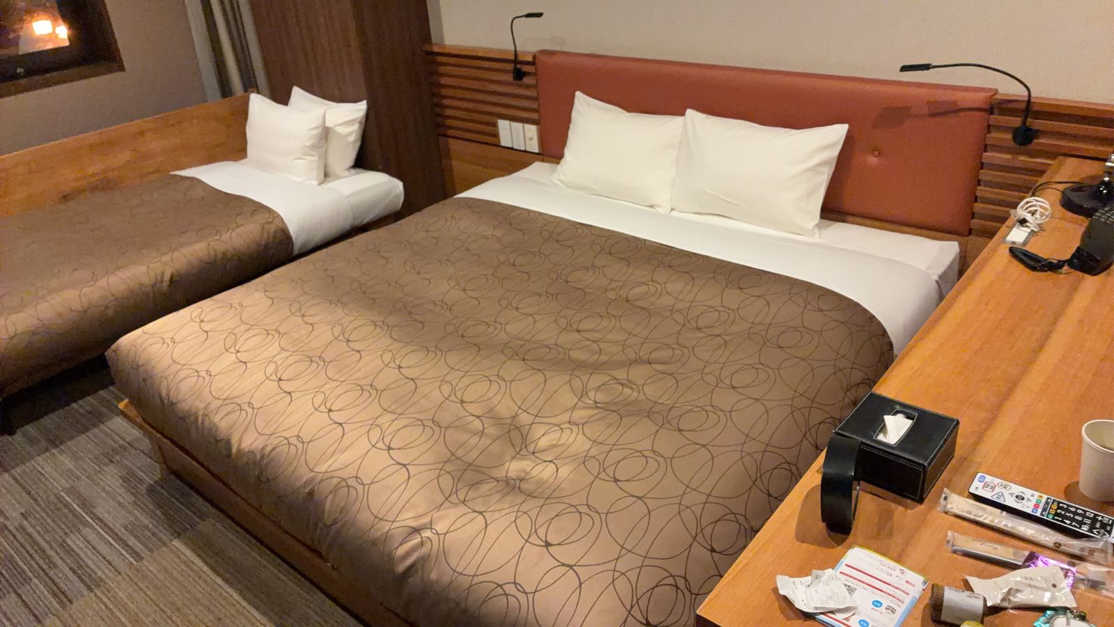 A plain business-hotel twin room, two beds made up and a desk along the wall