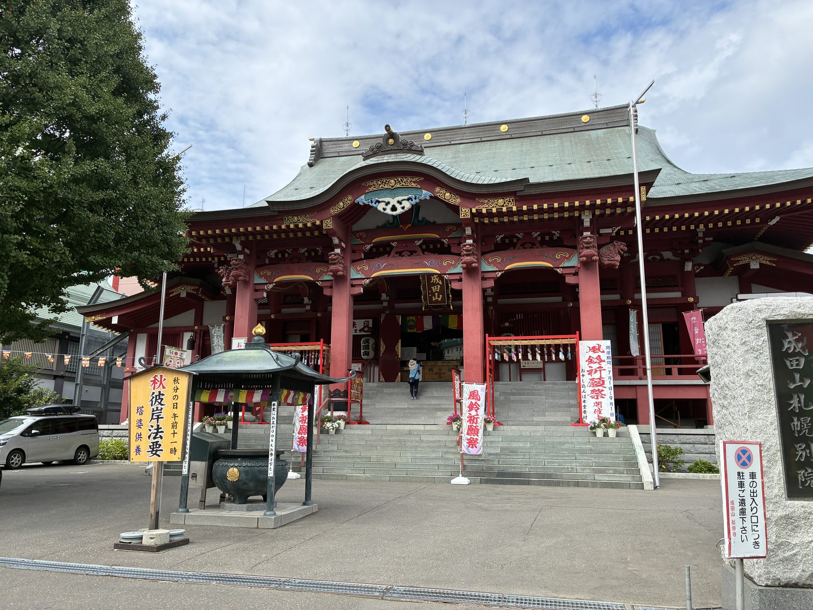 The vermilion main hall of Naritasan Sapporo, wind chimes strung across the approach